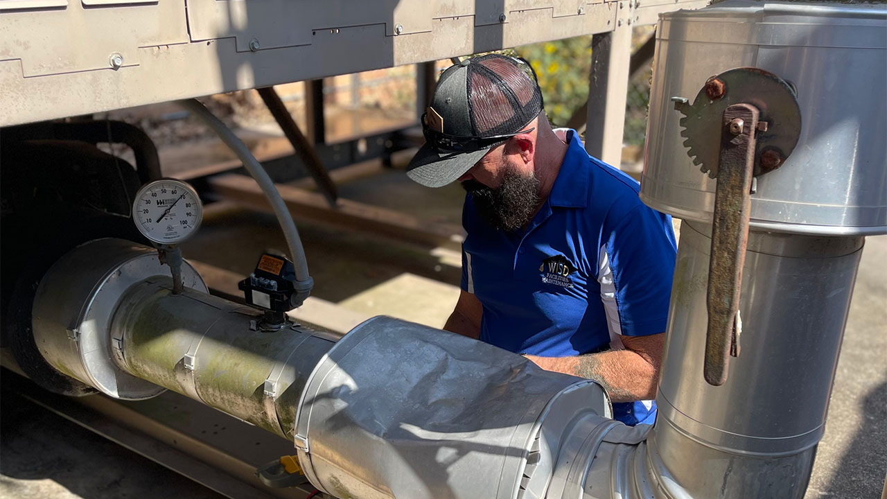  Man in a blue shirt inspecting industrial equipment, showcasing asset management processes for maintenance