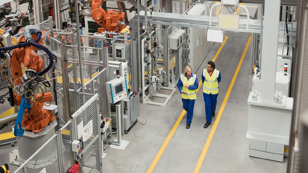  Manufacturing expert inspecting metal rolls while logging inventory on a tablet with asset tracking software