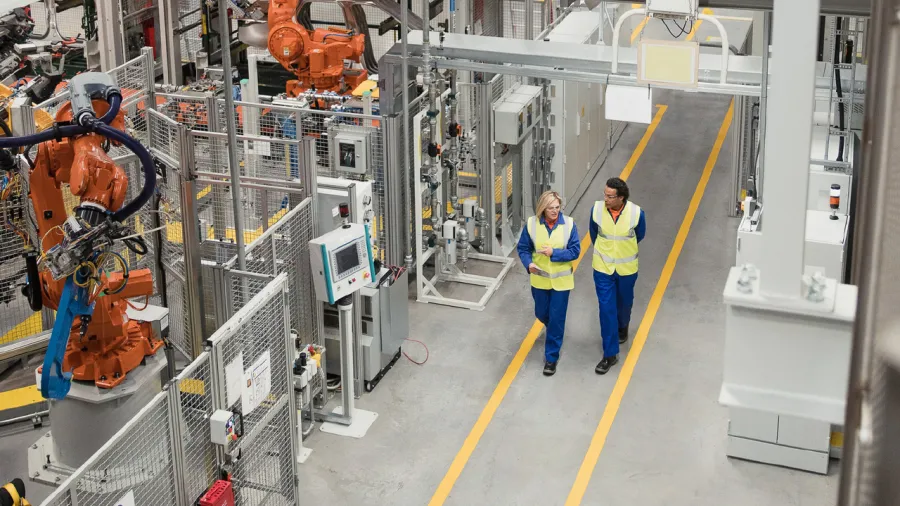  Manufacturing expert inspecting metal rolls while logging inventory on a tablet with asset tracking software