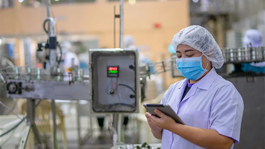 Food and beverage manufacturing worker looking at a tablet.