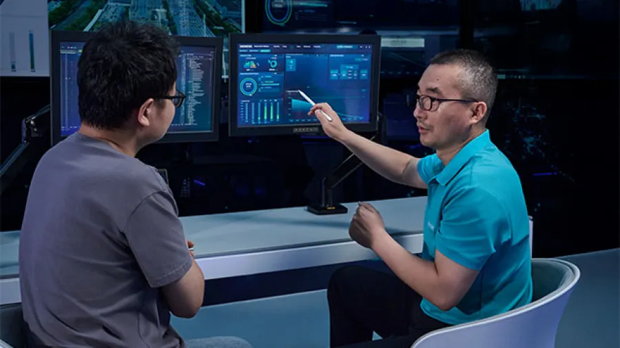 Two people looking at data on a monitor.