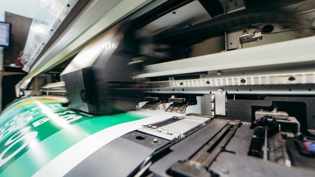  Close-up of fast-moving printing machinery printing a sign, symbolizing manufacturing asset productivity and precision.